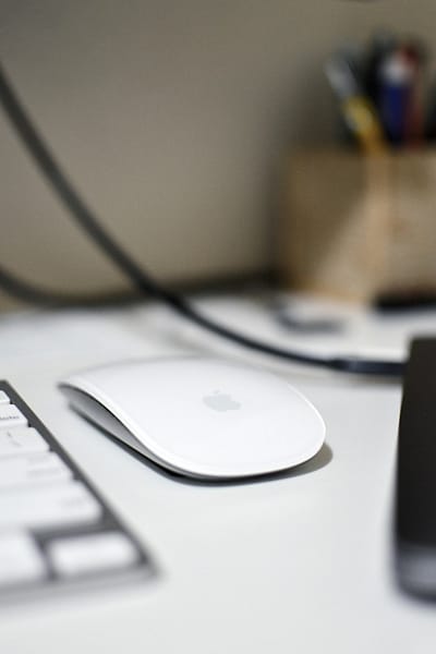 a computer mouse sitting on top of a white desk macbook mouse settings user interface system preferences.jpg
